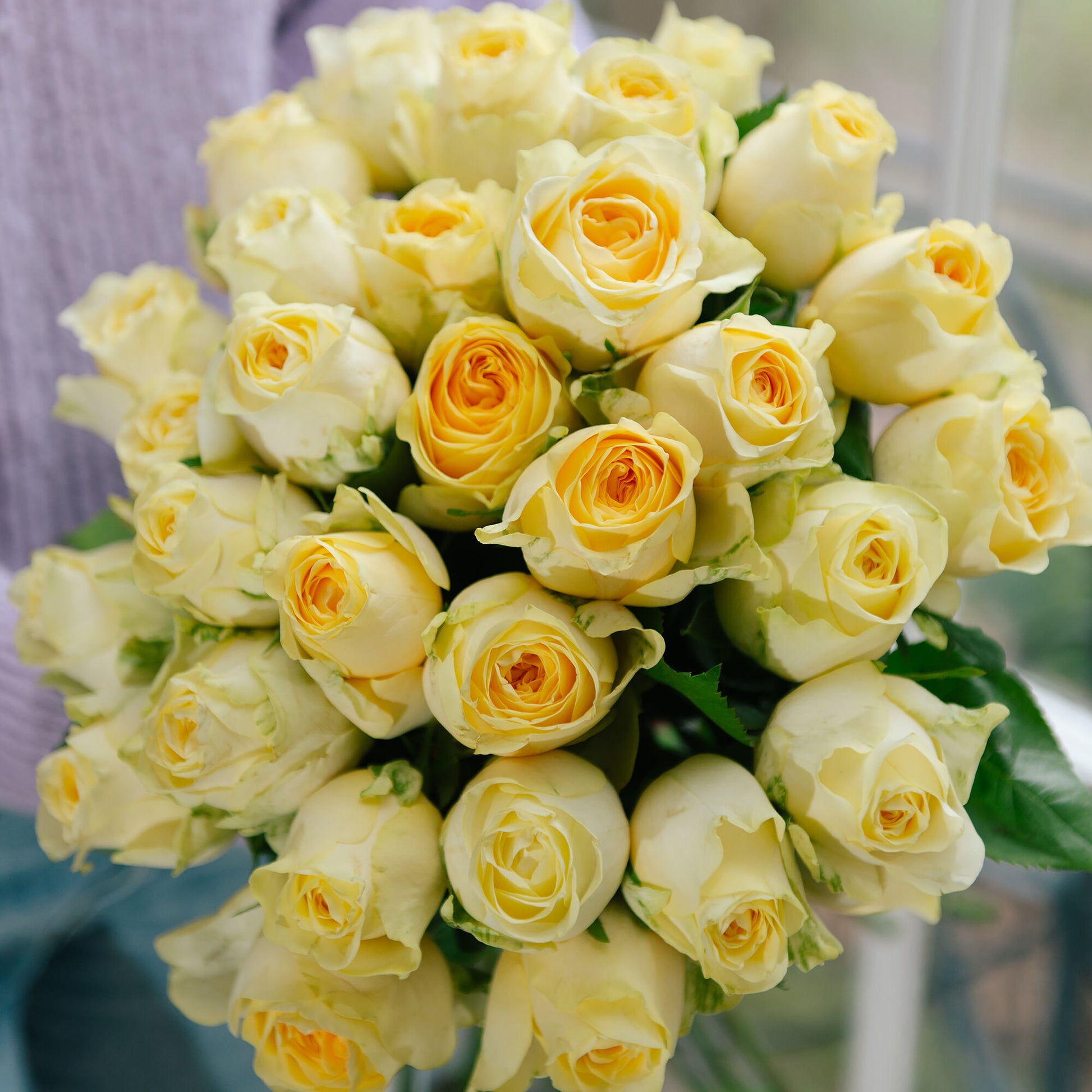 A beautiful bouquet of yellow Buttercup Garden Roses and complementary seasonal blooms arranged in a stunning display by expert florists. The bright yellow roses with their round heads and high petal counts bring a burst of color and happiness to any occasion.
