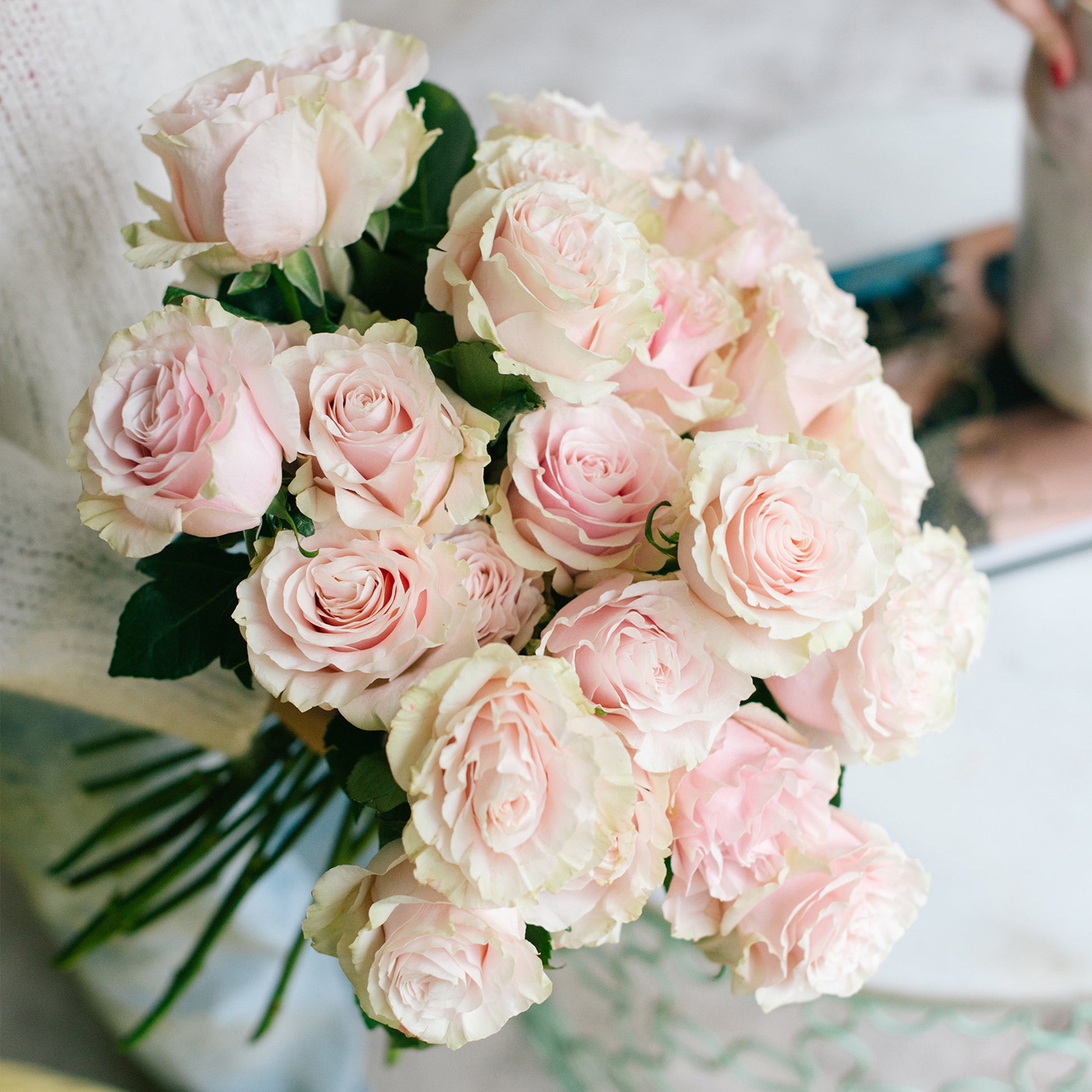 An expertly arranged single stem bouquet of light pink roses, with delicate green petals adding a beautiful contrast. Perfect for weddings, funerals, or any special occasion.